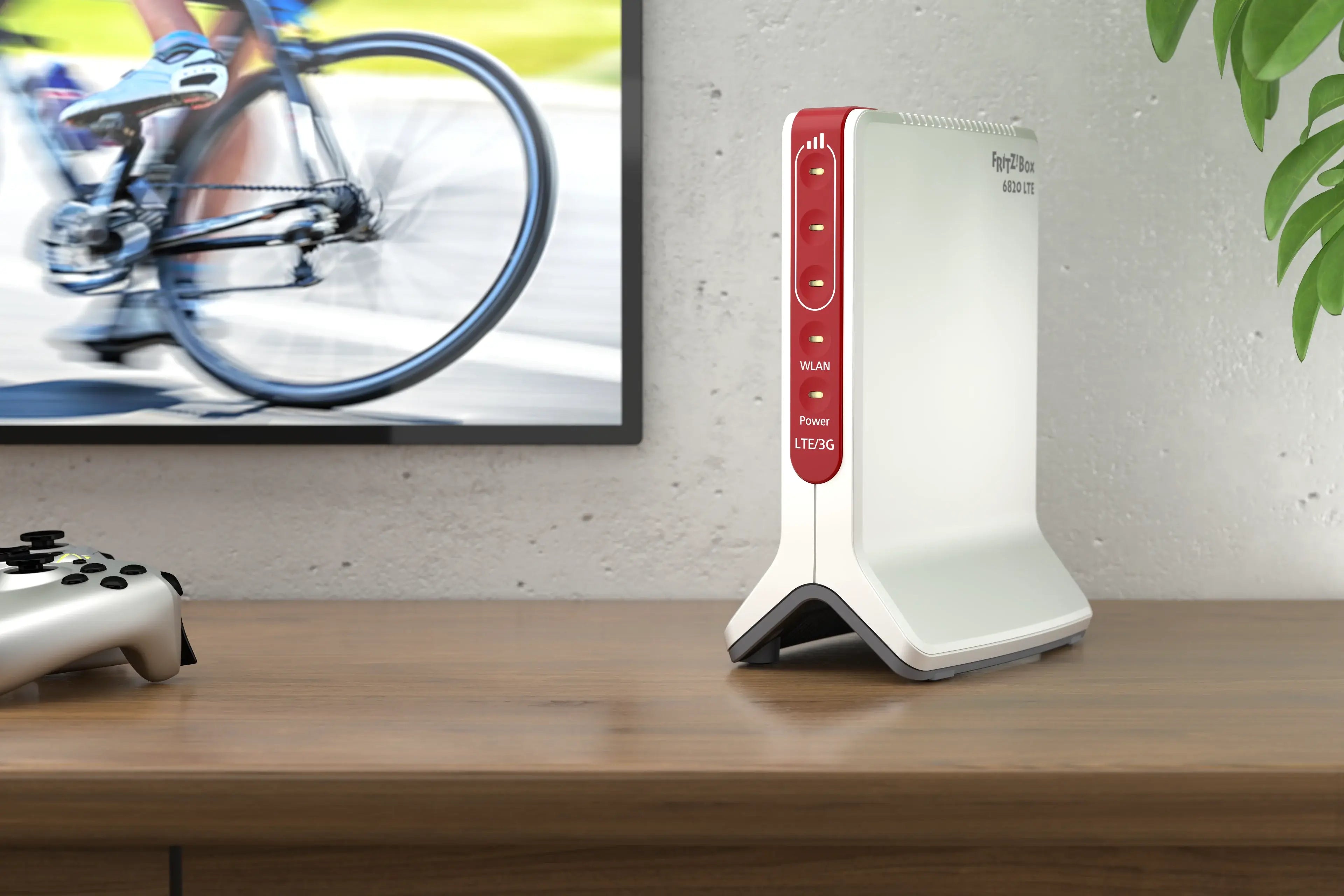 Modem auf Tisch neben Spielkonsole, während ein Radfahrer auf dem Bildschirm fährt.
