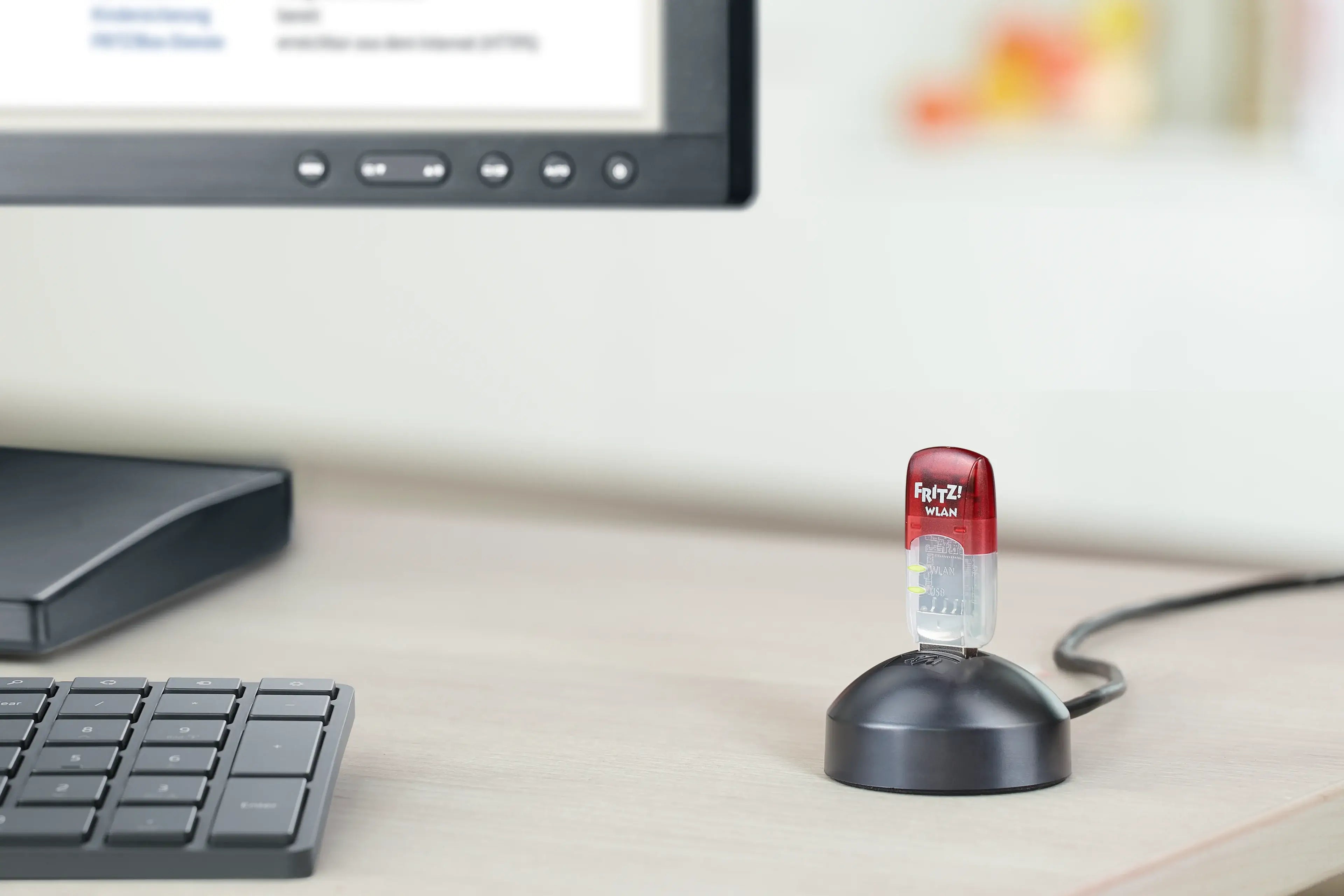 FRITZ!WLAN USB-Stick auf Schreibtisch neben Computer und Tastatur.