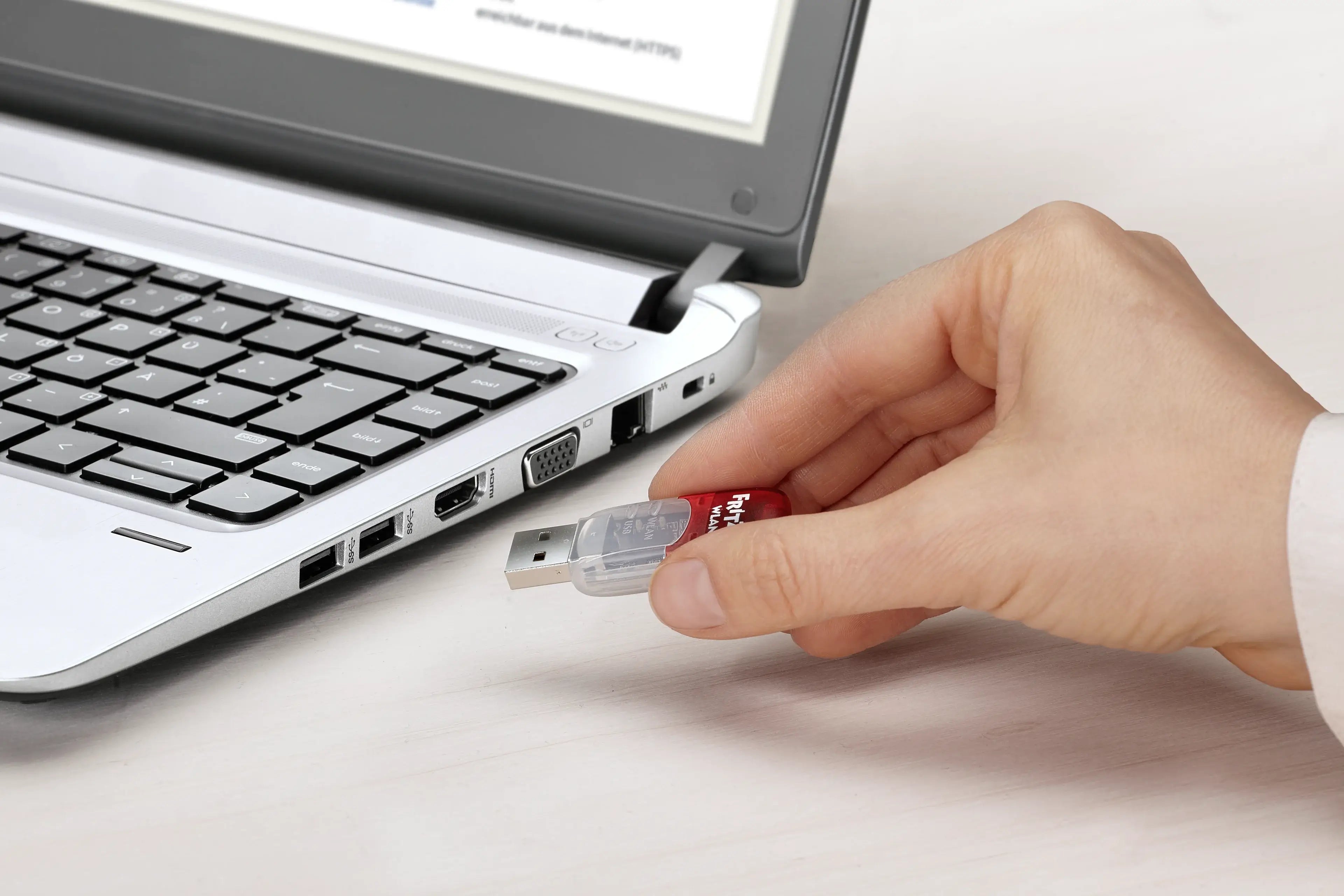 Eine Hand steckt einen USB-Stick in einen Laptop, um Daten zu übertragen oder zu sichern.